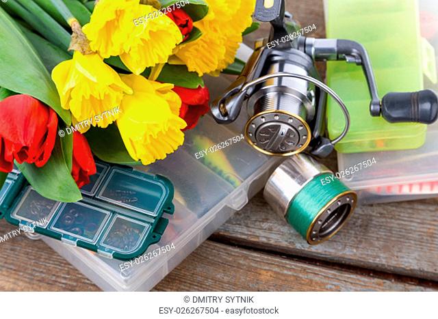 fishing tackles with bouquet of spring flowers narcissus and tulips on wooden background for outdoor active business for women gift