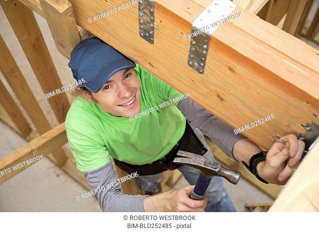 Caucasian man hammering nail at construction site