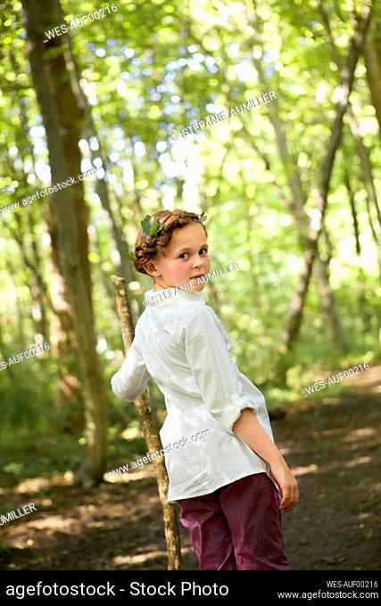 Portrait of girl with wood stick walking in forest