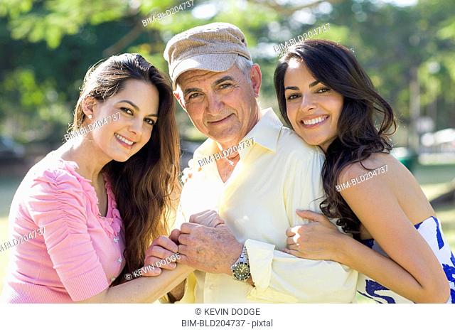 Hispanic father and daughters smiling outdoors