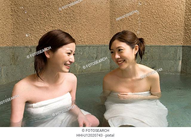 Two women in hot tub, smiling, front view, Japan