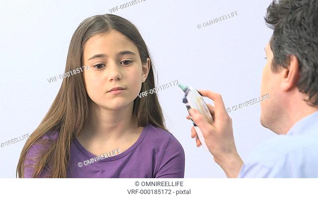 Male doctor taking young girl's temperature