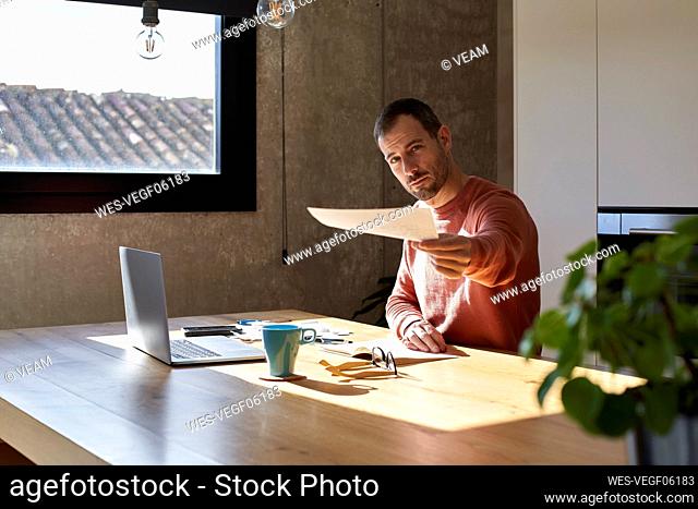 Man giving financial bill sitting at desk at home