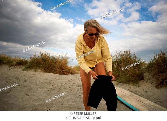 Senior woman putting on wetsuit