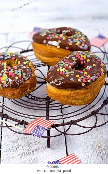 Three American cronuts with chocolate icing and sugar confetti