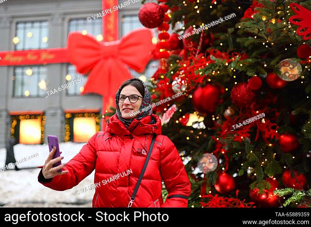 RUSSIA, MOSCOW - DECEMBER 19, 2023: A woman makes a selfie during the opening of an exhibition of designer Christmas trees in Kuznetsky Most Street