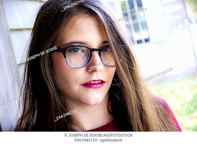 A casual portrait of a 26 year old woman with long brown hair and big glasses, outdoors