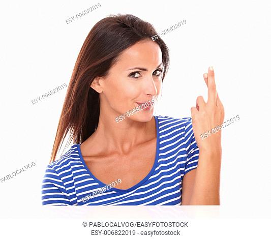 Cute lady in blue t-shirt making a lucky sign while looking at camera in white background