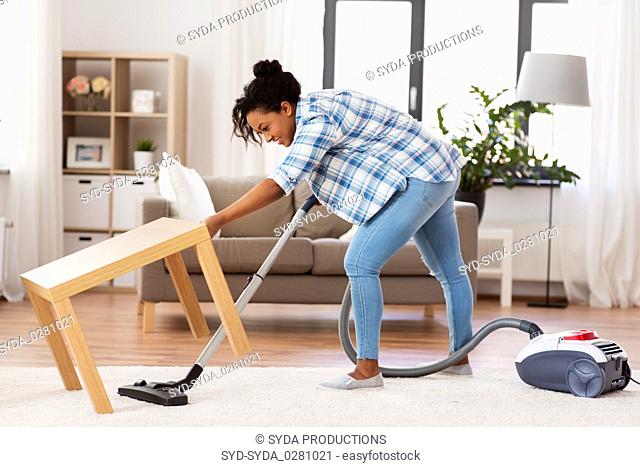 woman or housewife with vacuum cleaner at home