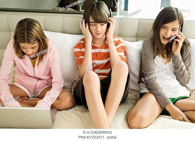 Boy sitting with two girls on the bed