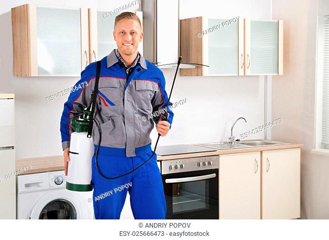 Young Happy Pest Control Worker With Insecticide Sprayer In Kitchen Room