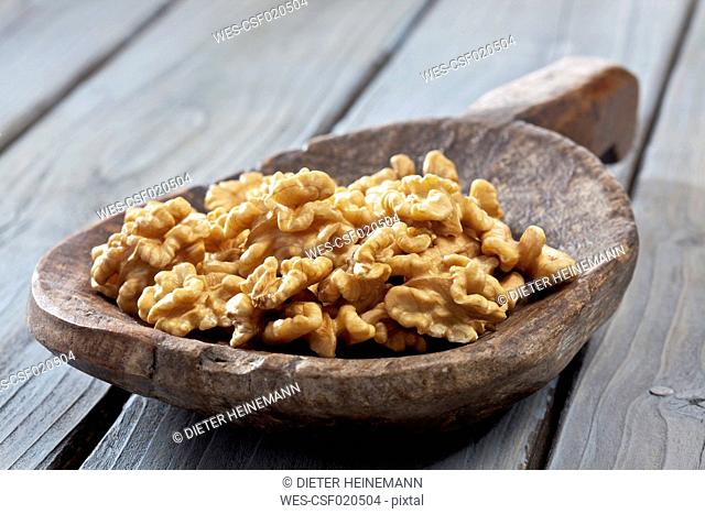 Wooden shovel with cracked walnuts (Juglans) on wooden table