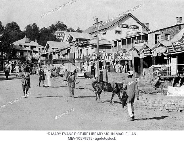 Street scene in Murree, India (now part of Pakistan), with a restaurant, shops and pedestrians