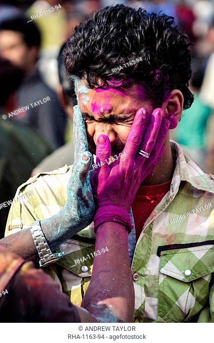 Two men exchange coloured powder during Holi festival celebrations, Basantapur Durbar Square, Kathmandu, Nepal, Asia