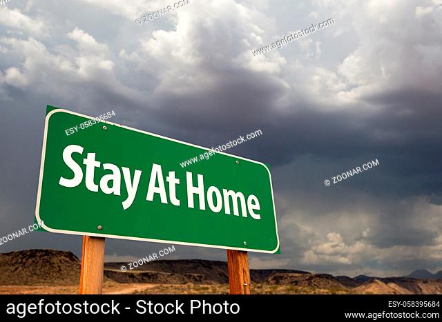 Stay At Home Green Road Sign Against An Ominous Cloudy Sky