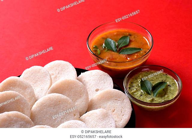 Idli with Sambar and coconut chutney on red background, Indian Dish: south Indian favourite food rava idli or semolina idly or rava idly