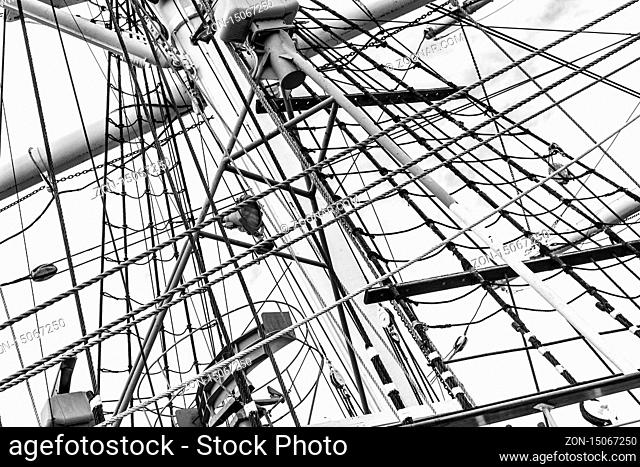 Monochrome image of mast with rigging and rolled up sails of old polish sailing ship Dar Pomorza