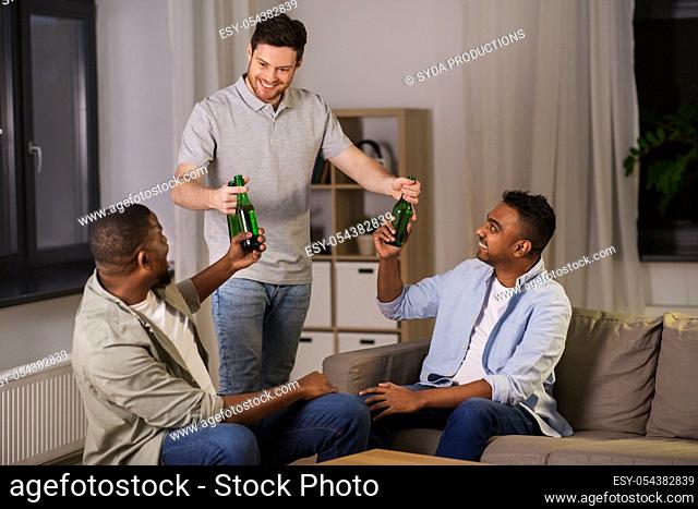 happy male friends drinking beer at home at night
