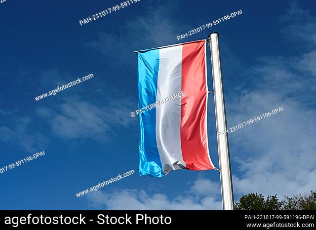 13 October 2023, Luxembourg, Vianden: The national flag of the Grand Duchy of Luxembourg flies in the wind against a blue sky