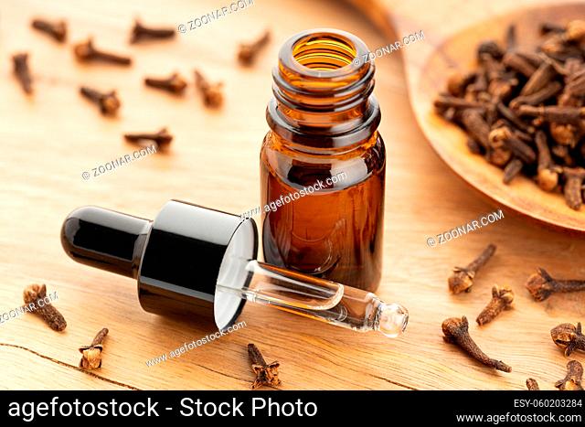 Clove essential oil on bottle on wooden table. Alternative medicine