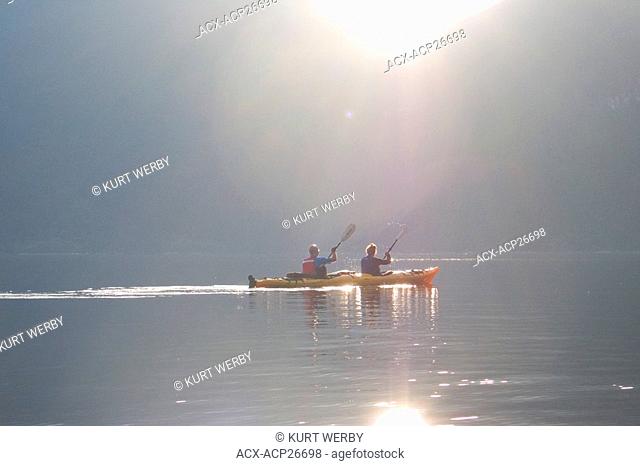Kayakers paddling towards Harmony Islands in Hotham Sound at sunset along the British Columbia coast Canada