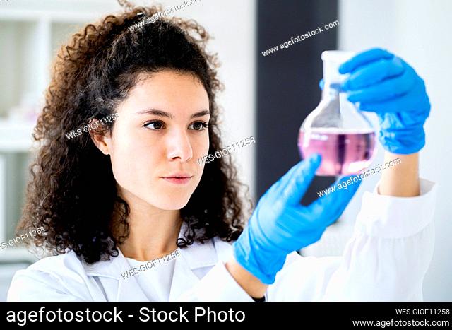 Young female doctor experimenting with chemical solution at clinic