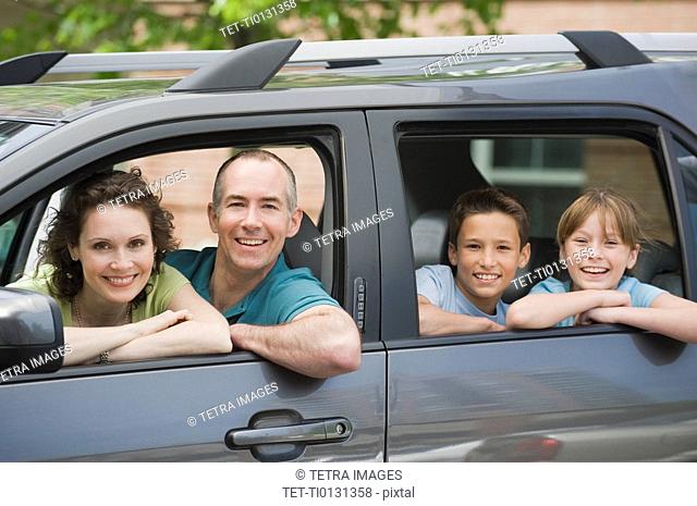 Family with two children looking out car windows