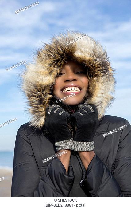 Smiling woman wearing coat on beach