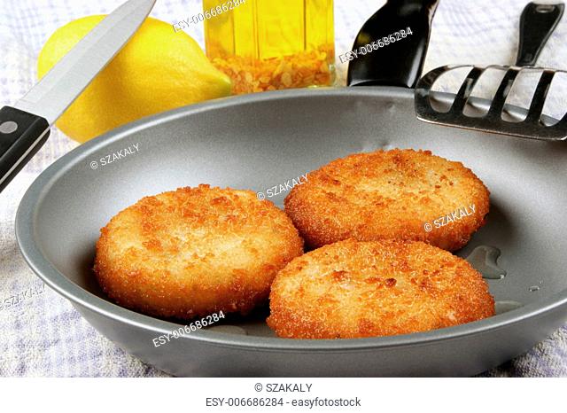 three freshly fried fish cakes in a pan
