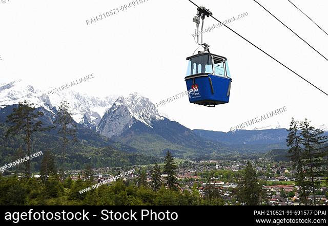 21 May 2021, Bavaria, Garmisch-Partenkirchen: A gondola of the Wankbahn goes towards the summit, in the background the Wetterstein mountains can be seen