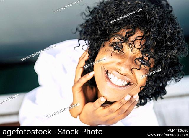 directly above shot of happy african american woman with curly hair looking up at the camera. portrait of joyful black woman in white dress