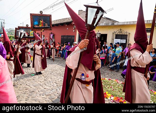 Antigua, Guatemala: March 18 2018: People with pointed hood costumes carrying paintings of the way of the cross at the procession of San Bartolome de Becerra in...