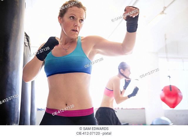 Determined, tough female boxer shadowboxing in gym