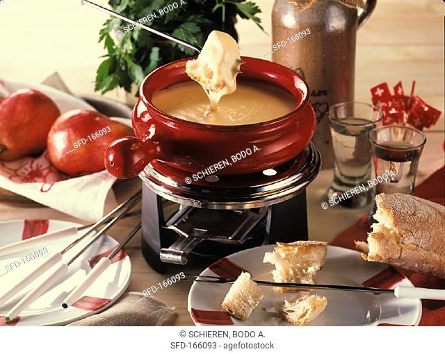 Cheese fondue in a red caquelon (fondue pan)