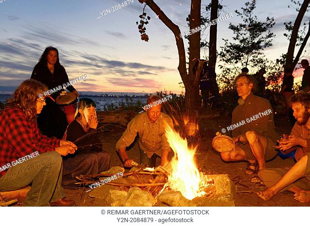 Group of people around a campfire on Hanlan's Point Beach Toronto Islands at dusk