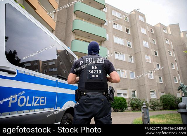 15 July 2020, Berlin: A policeman is standing in front of a building during a police operation as part of a large-scale raid against suspects from the Islamist...
