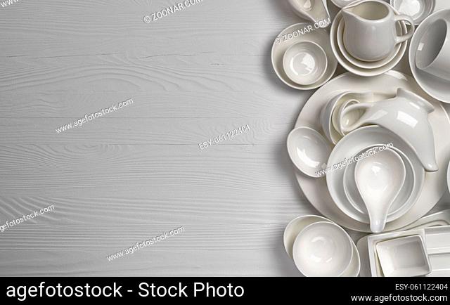 Set of empty dishware on white background with copy space, clean tableware assortment on wooden table, top view