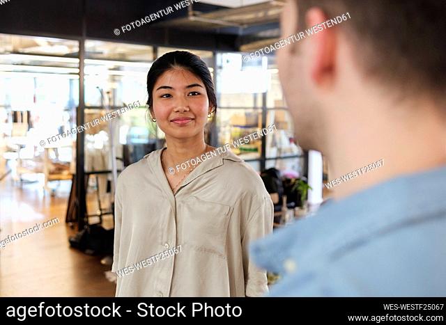Young woman talking to colleague in modern coworking space