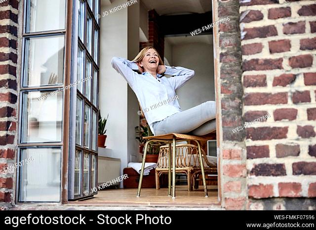 Happy woman sitting on chair at terrace