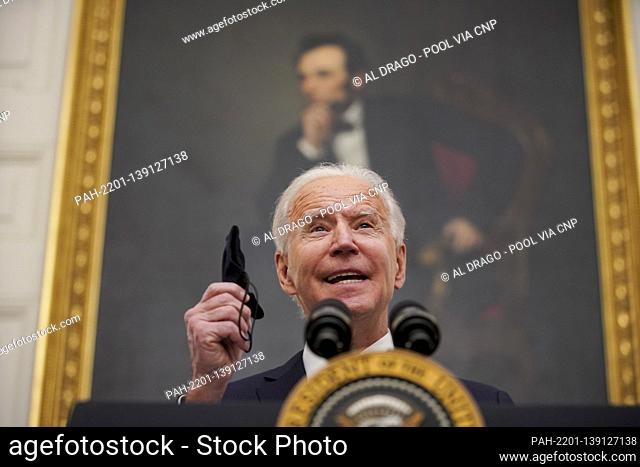 U.S. President Joe Biden holds a protective mask while speaking during an event on his administration's Covid-19 response in the State Dining Room of the White...