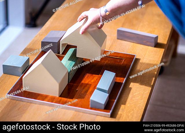 06 May 2021, Mecklenburg-Western Pomerania, Koserow: A museum employee demonstrates on a model the arrangement of the buildings around the former wagon on the...