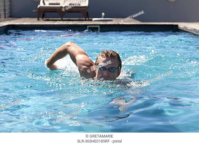 Man in goggles swimming in pool