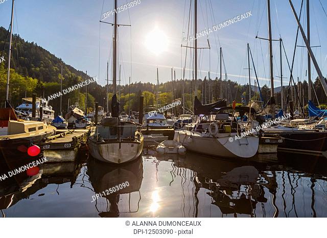 A tranquil sunny afternoon as the sun sets behind the marina at Snug Cove, Bowen Island on the West Coast near Vancouver; Bowen Island, British Columbia, Canada