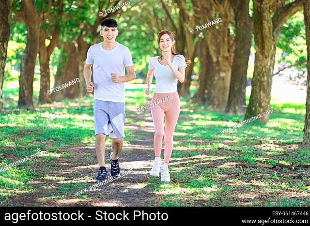 young couple jogging together in the park on sunny day