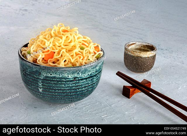 Instant noodles bowl with carrot and scallions, with chopsticks and sake, vegetable soba bowl with a place for text
