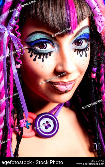 Portrait of a stylish young woman with multicolored dreadlocks and with stylish make-up in doll style. Creative make-up.Fantasy dress