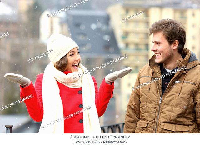 Happy couple enjoying snow in a snowy day in the street of a town