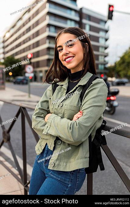 Smiling woman with arms crossed at city street