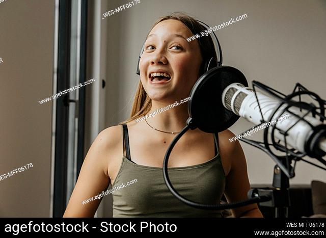 Close-up of teenage girl singing over microphone in studio