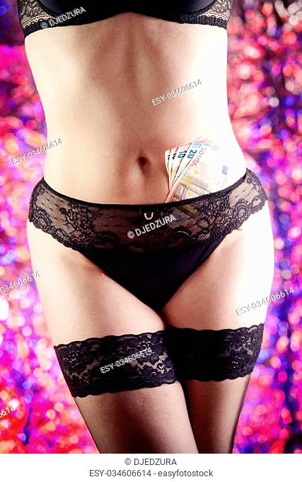 Photo of a woman prostitute or striptease dancer in black underwear and black stockings. The woman has eurobanknotes in her panties